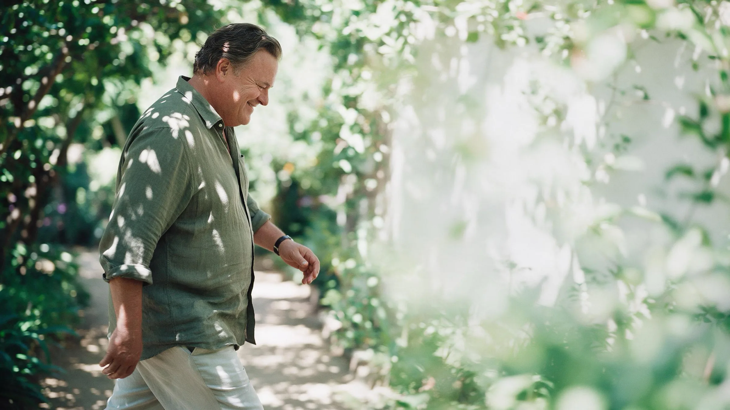 A man walking a shaded garden path